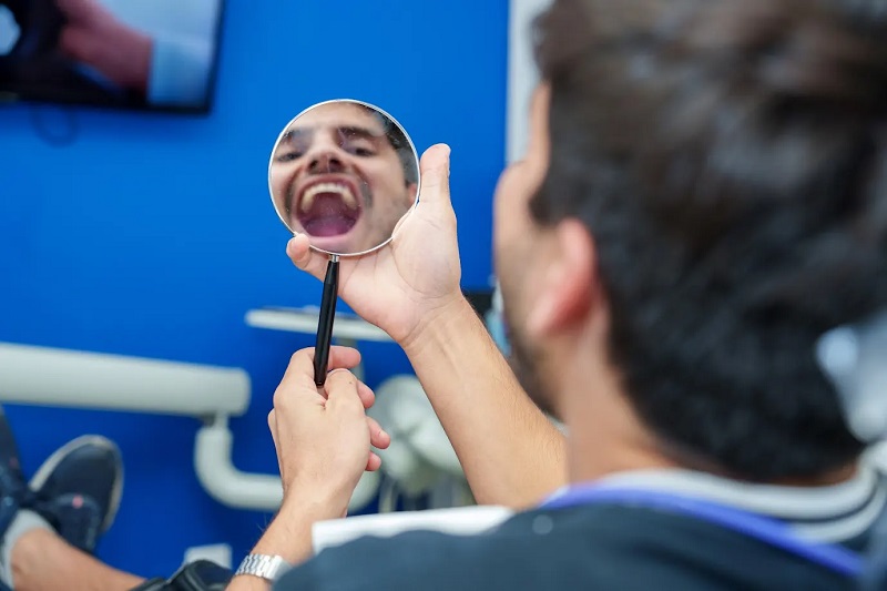 Patient looking at teeth in mirror after treatment